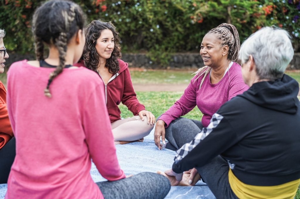 Multi generational women having fun together sitting outdoors at city park