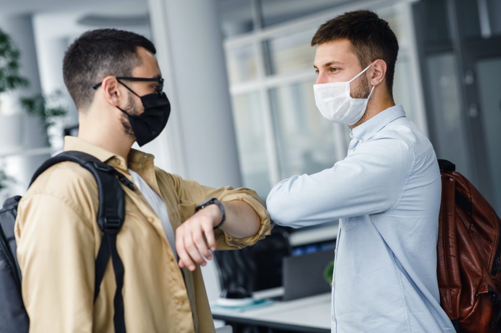 Coworking office and social distance during quarantine covid-19. Millennial guys in protective masks